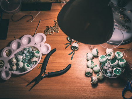 Buds of polymer clay, round pliers, working space.   Beautiful original beads from polymeric hand-worked clay.の写真素材