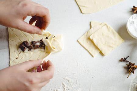 Cooking delicious sweets with jam and and powder to tea.Top view. Womans hands are preparing a cake by adding dough. On a white table lies a few dough. Sunny morning.Flat lay.の写真素材