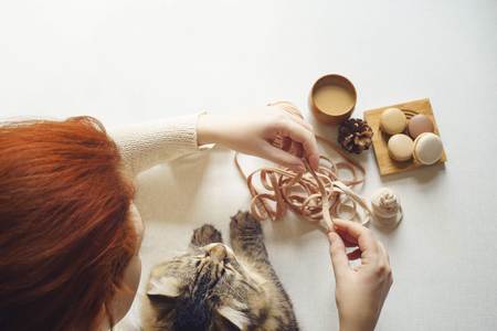View of table above where cat and girl with red hair drink coffee and unravel tangle. Spotted kitty and female with red hair drink espresso, get macarons and knits yarn. Flat lay. Top view.の写真素材