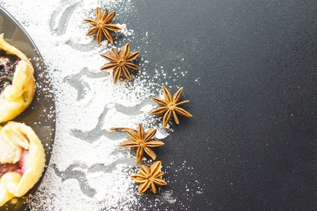 Scattered with powder and cinnamon on a black table. top view.Homemade cookies with jam, on a black desk. black background. Cooked at home buns are waiting for their tea. View from above.の写真素材