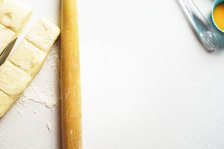 Food ingredients in kitchen on white background. Cooking concept. Top view. Battledore with a piece of duff cut in half with a knife on a white desk.の写真素材