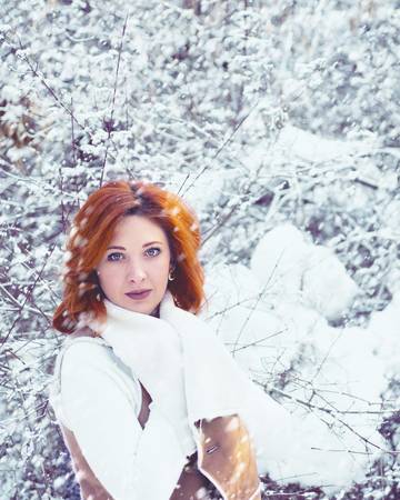 Stylish young girl walking in a winter day on the background of the park with snow.の写真素材