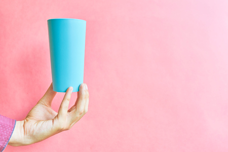 Colorful plastic cup. Hand holding empty plastic cup ice tea on pink background.の写真素材