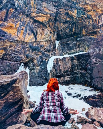 The woman sitting on the rock mountain. Young yoga woman sit meditation on mountain peak rock.の写真素材