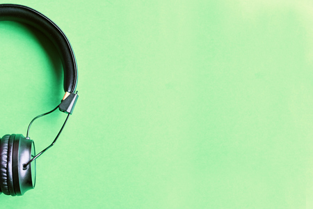 Wireless black headphones on colorful green background. Earphones on lime background with copy space for text top view.の写真素材