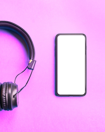 Headphones and smartphone on colorful background. Flat lay concept: headphones and telephone on pink pastel backgrounds.の写真素材