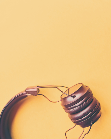 Wireless headphones on colorful background. Black eardphones on a yellow background, top view, copyspace.の写真素材