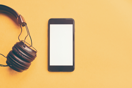 Black wireless headphones and black smartphone on colorful yellow background, flat lay. Mock-up, design elementsの写真素材