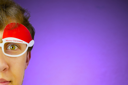 Young hipster with green eyes with glasses with the words merry Christmas on a bright purple background.の写真素材