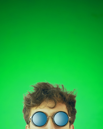 Man looks out. Guy with glasses looking at camera on green background. Copy space for text. Crop 4x5 verticalの写真素材
