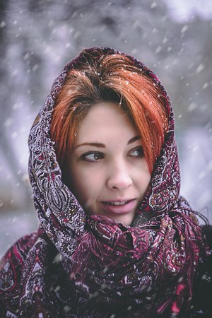 Portrait of a woman in a cold winter. Portrait of woman in winter clothing looking at camera in snowy park.の写真素材