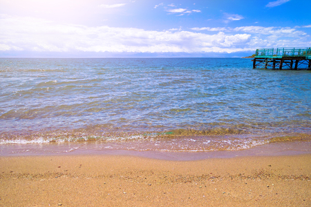 Sandy shore. calm ocean. Large pier. Beautiful calm beach and cloudless blue sky with ocean at low tide, with copy space.の写真素材