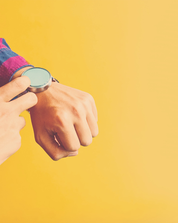 Man wear smart watch. Concept for business, omnichannel, multi payment, lifestyle using and other. Smartwatch - modern gadget with empty display, copy space. Yellow backgroundの写真素材