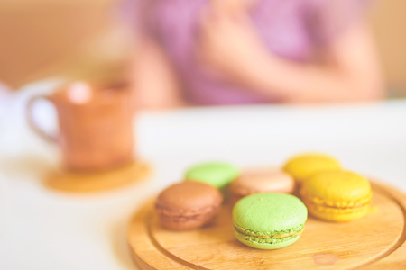 Cute young beautiful caucasian woman is enjoying her morning breakfast of black coffee, French macarons served on a tray. Breakfast in bed conceptの写真素材