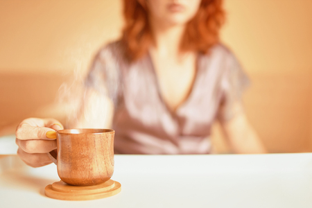 Cute woman in a purple silk robe drinking coffee early in the morning in bed. Wooden cup of latte on the white tray. Breakfast concept. Copyspace fot textの写真素材