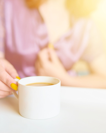 Awesome pretty woman in a purple silk robe drinking coffee early in the morning in bed. White cup of latte on the tray. Breakfast concept, sun flare, vertical cropの写真素材