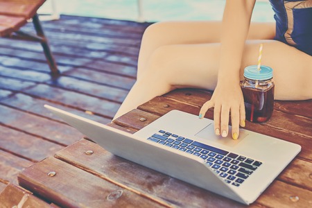 Tourist girl using a laptop on summer vacation in a terrace on the beach.の写真素材