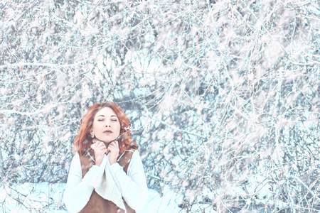 Outdoor portrait of young pretty beautiful woman in cold winter weather in park in snowy weatherの写真素材