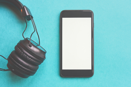 Wireless headphones and mockup smartphone on colorful background. Flat lay concept: headphones and telephone on blue pastel backgrounds.の写真素材