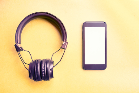 Wireless headphones and mock-up smartphone on colorful background. Earphones and telephone on yellow background.の写真素材