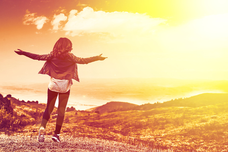 Beauty woman outdoors enjoying nature. Pretty young woman in field at sunset in the mountainsの写真素材