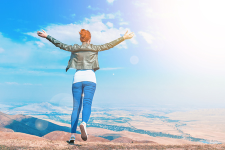Amazing Woman Outdoors raising hands in sunlight rays. Beautiful Teenage Model girl running on the mountain, Sun Light. Glow Sun. Free Happy Woman. Feel Flyの写真素材