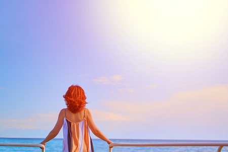 Behind girl on pier. Woman standing on the pier at the railing at sunrise.の写真素材