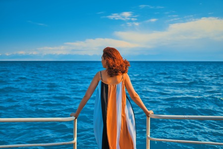 Behind girl on pier. Woman in colorfull dress standing on the pier.の写真素材