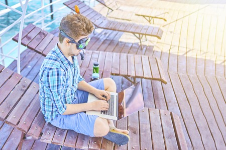 Freelancer concept. A man in an underwater mask during the weekend, at sea, working on a laptop.の写真素材