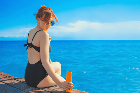 Awesome cute female person applying sun protection lotion. Tanned pretty woman body applying sun uv protection cream.の写真素材