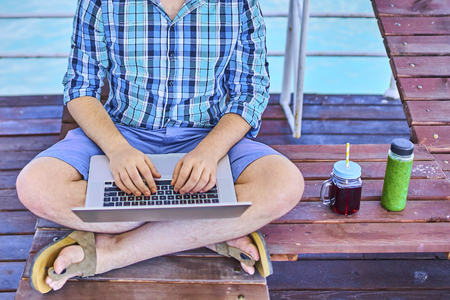 A man during the weekend, at sea, working on a laptop. Freelancer conceptの写真素材