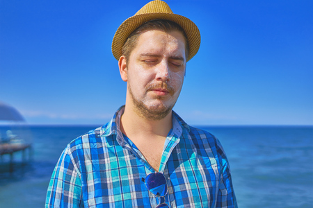 Guy with sun protection lotion cream on the face. Man Tanning Using Sun Block Body Cream On Summer Beach.の写真素材