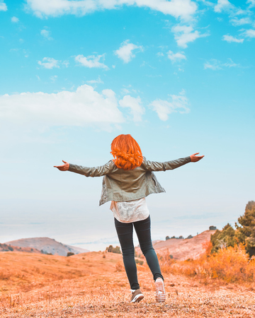 Autumn Girl enjoying nature in the mountains. Beauty Female Outdoors raising hands in sunlight rays. Beautiful Teenage Model girl running on the Field, Sun Light. Glow Sun. Free Happy Woman.の写真素材