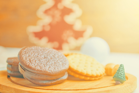 Miniature Christmas tree with cookies on the table on a festive evening with big red christmas tree on backgroundの写真素材