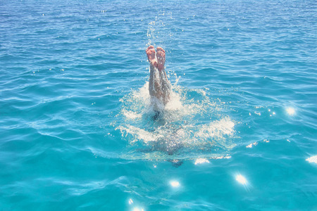 Man dives into the sea on vacation. Feet sticking out of the waterの写真素材