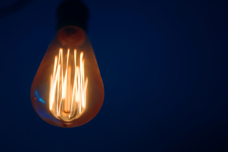 Glowing Edison lamp on dark blue backgroundの写真素材