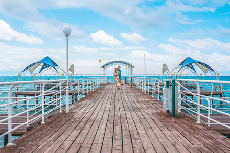 Young couple resting on the beach on their honeymoon. Man and woman hugging on the pier at seaの写真素材