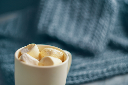 Strong coffee with marshmallow on the table with a warm blanketの写真素材