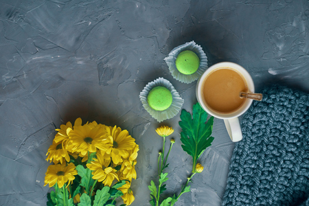 Hot coffee with milk or cream and green macaroons on the loft table in a romantic setting with chrysanthemums nearbyの写真素材