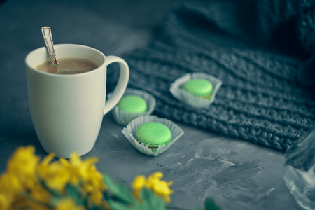 Hot coffee with milk or cream and green macaroons on the loft table in a romantic setting with chrysanthemums nearbyの写真素材