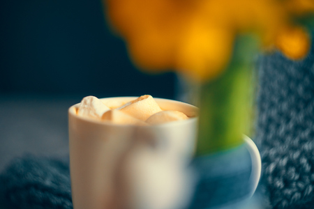 White Cup of strong coffee with marmalade next to the yellow chrysanthemum flowers in a glass transparent vaseの写真素材
