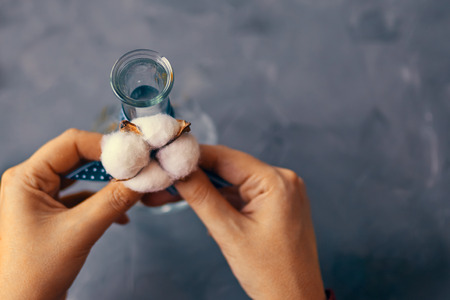 Woman ties the cotton to the vase for flowers on a loft tableの写真素材