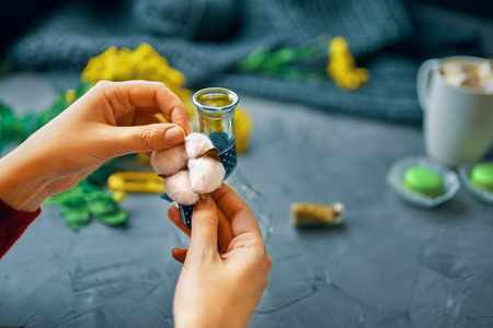 Woman ties the cotton to the vase for flowers on a loft tableの写真素材