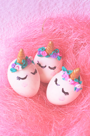 Three Easter eggs unicorns in a pink nestの写真素材