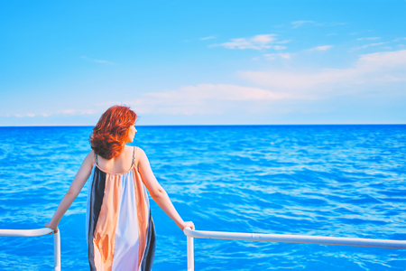 Behind girl on pier. A redhead woman stands on a pier on a hot day in the sun.の写真素材