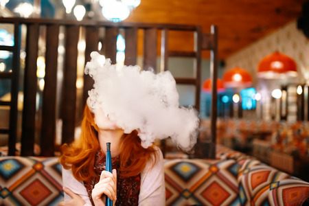 Young woman smoking hookah at the restaurant
