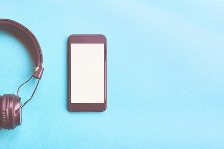Headphones and smartphone on colorful background. Flat lay concept: headphones and telephone on blue pastel backgrounds.の写真素材