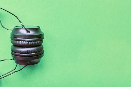 Wireless portable headphones on colorful green background.