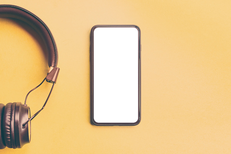 Headphones and smartphone on colorful background. Phone and Headphones for music sound Isolated on yellow background.の写真素材