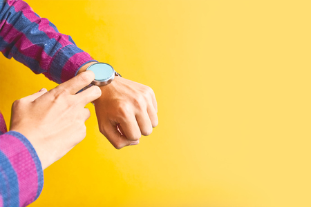 Man using smart watch for omnichannel. Smartwatch - modern digital gadget with empty display, copy space. Yellow backgroundの写真素材